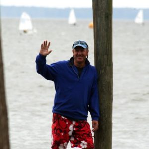 Coach Craig waving with sailboats in the background